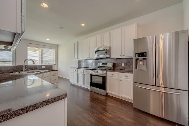 kitchen with decorative backsplash, white cabinets, dark hardwood / wood-style floors, and appliances with stainless steel finishes