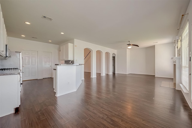 unfurnished living room featuring a fireplace, ceiling fan, plenty of natural light, and dark hardwood / wood-style flooring