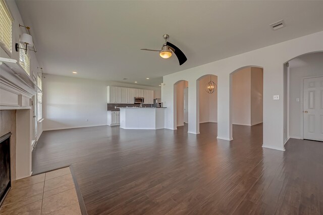 unfurnished living room featuring hardwood / wood-style floors, ceiling fan, and a fireplace