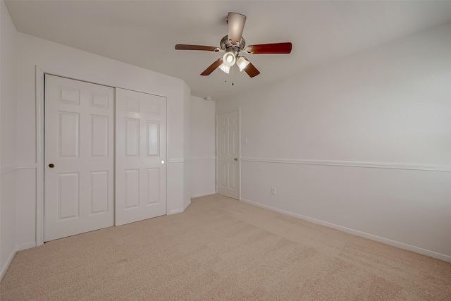 unfurnished bedroom featuring ceiling fan, light carpet, and a closet