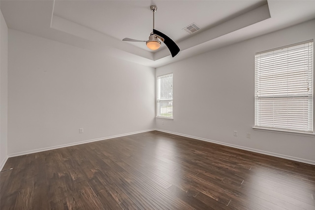 spare room featuring ceiling fan, dark hardwood / wood-style flooring, and a tray ceiling