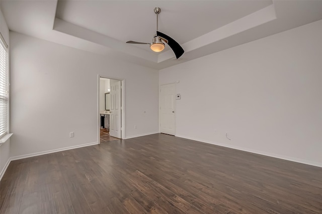 unfurnished room featuring ceiling fan, dark hardwood / wood-style flooring, and a tray ceiling