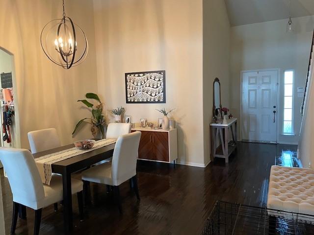 dining space featuring an inviting chandelier, dark hardwood / wood-style flooring, and a high ceiling