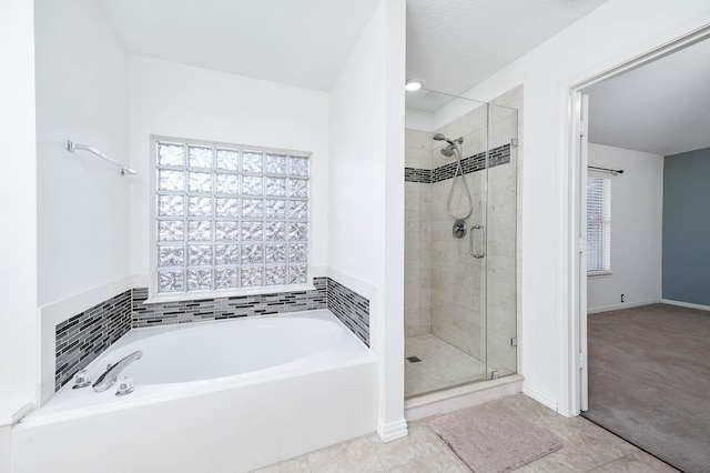 bathroom with tile patterned flooring, a textured ceiling, and separate shower and tub