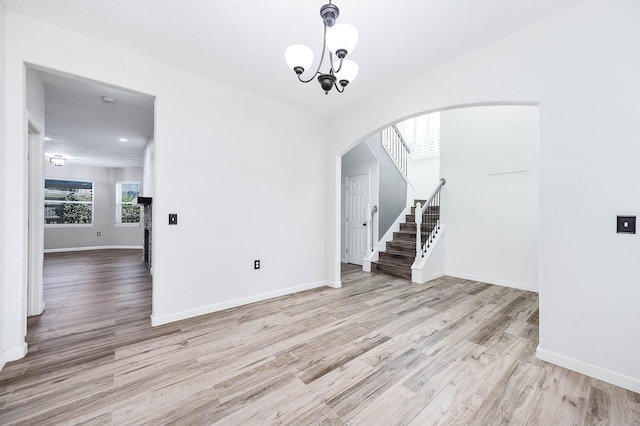 unfurnished room with light hardwood / wood-style floors and a notable chandelier