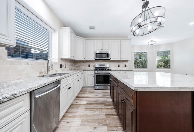 kitchen featuring backsplash, white cabinets, stainless steel appliances, sink, and a chandelier