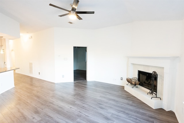 unfurnished living room featuring hardwood / wood-style flooring, ceiling fan, and a premium fireplace