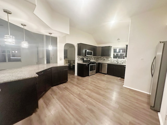 kitchen with appliances with stainless steel finishes, backsplash, sink, decorative light fixtures, and light hardwood / wood-style flooring