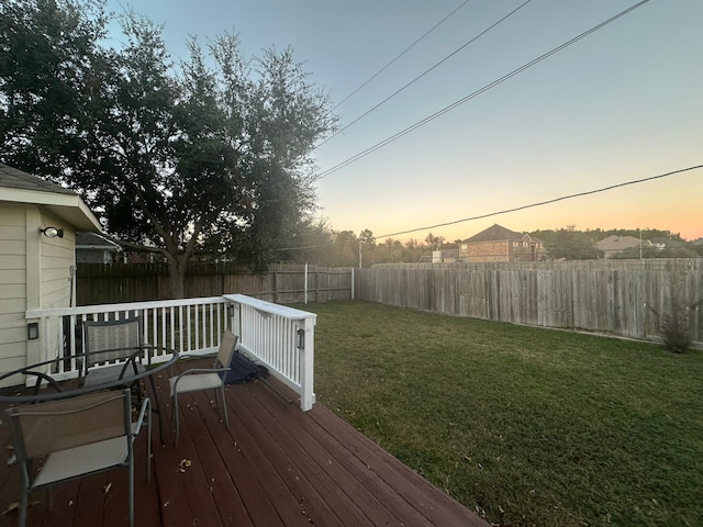 deck at dusk featuring a lawn