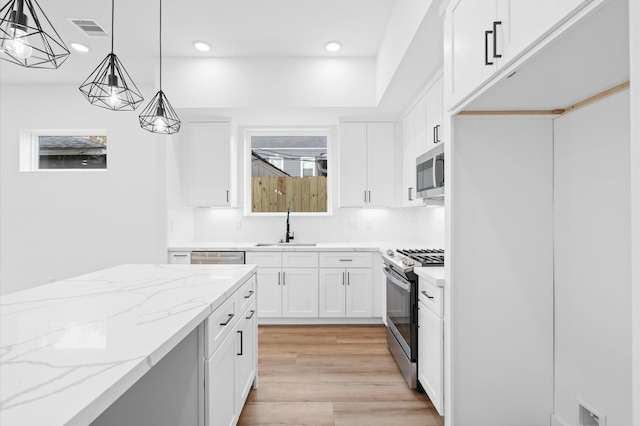 kitchen with white cabinetry, hanging light fixtures, stainless steel appliances, and sink