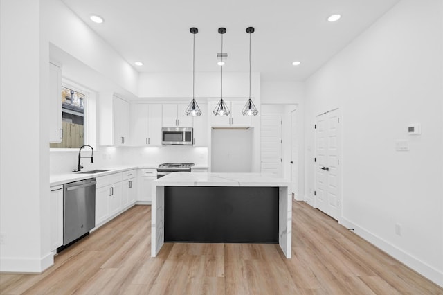 kitchen with a center island, white cabinets, sink, light stone countertops, and appliances with stainless steel finishes