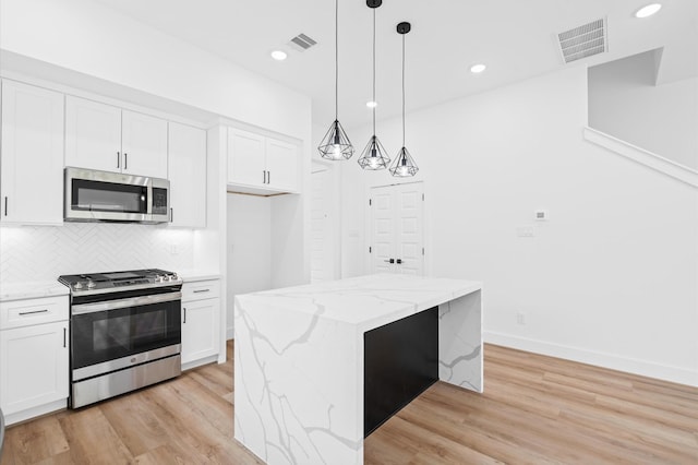 kitchen featuring a kitchen island, white cabinetry, stainless steel appliances, and hanging light fixtures