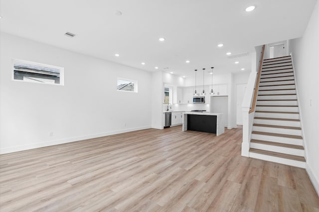 unfurnished living room featuring light wood-type flooring and sink