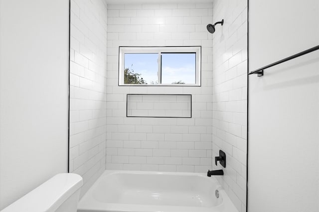 bathroom featuring toilet and tiled shower / bath