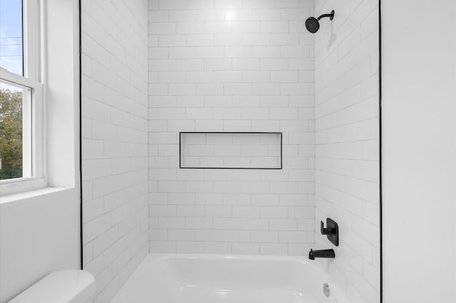 bathroom featuring toilet and tiled shower / bath