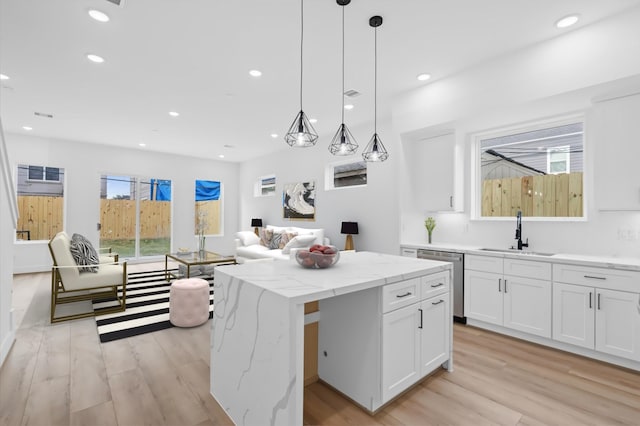 kitchen with a center island, dishwasher, sink, pendant lighting, and white cabinets