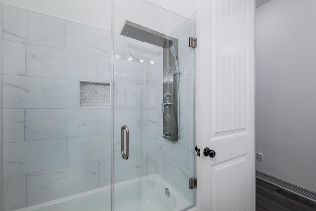 bathroom featuring enclosed tub / shower combo and wood-type flooring