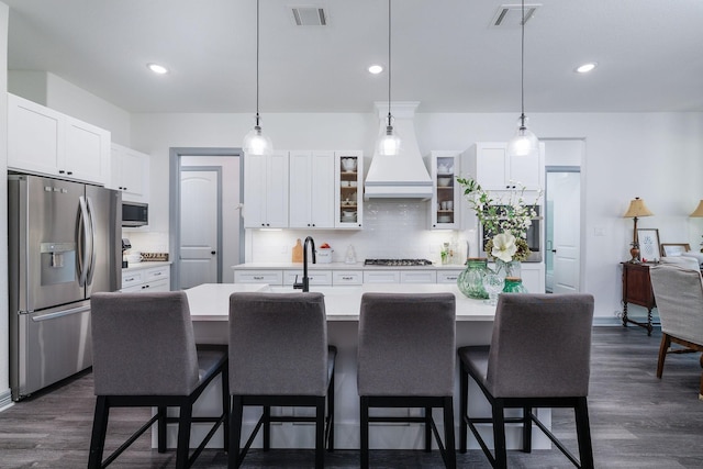 kitchen with backsplash, pendant lighting, a center island with sink, and stainless steel appliances