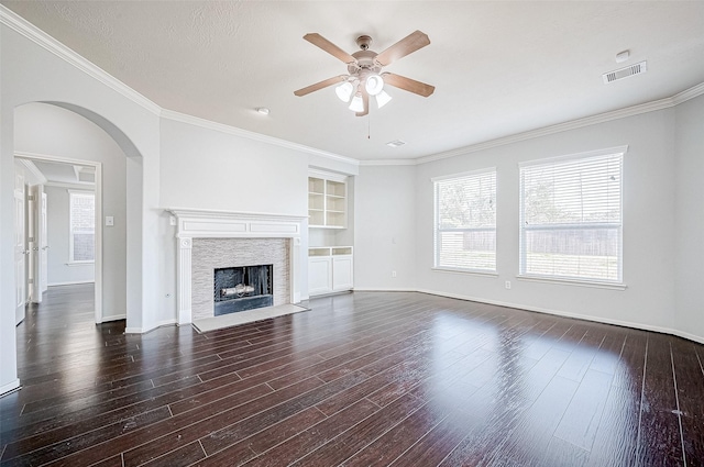 unfurnished living room featuring ornamental molding, ceiling fan, dark wood-type flooring, a textured ceiling, and built in shelves