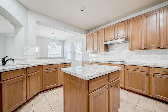 kitchen with hanging light fixtures, light tile patterned flooring, a center island, and tasteful backsplash