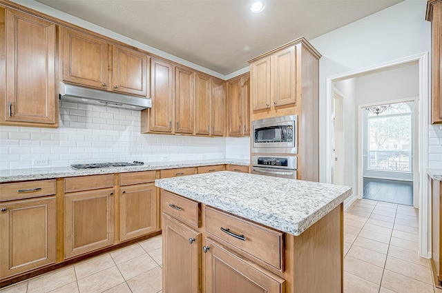 kitchen with tasteful backsplash, appliances with stainless steel finishes, a center island, and light tile patterned floors