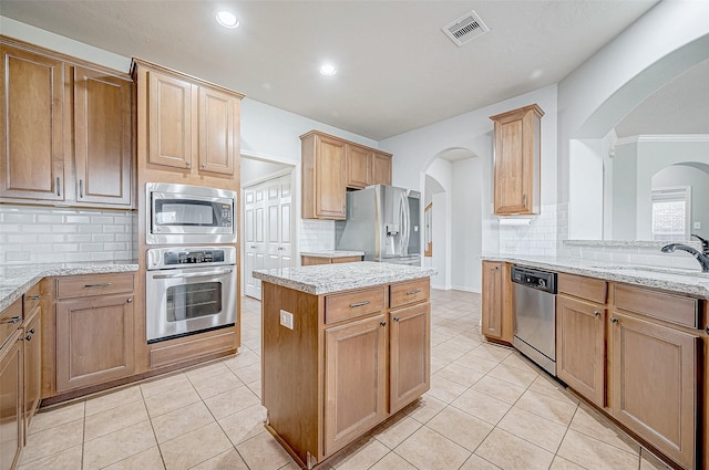 kitchen with light tile patterned flooring, appliances with stainless steel finishes, sink, and light stone counters