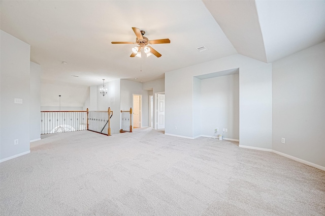 spare room featuring lofted ceiling, ceiling fan with notable chandelier, and light colored carpet