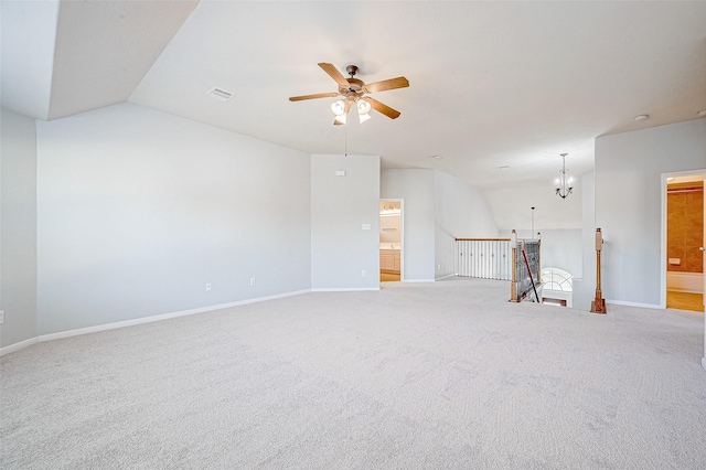 spare room with ceiling fan with notable chandelier, light colored carpet, and vaulted ceiling