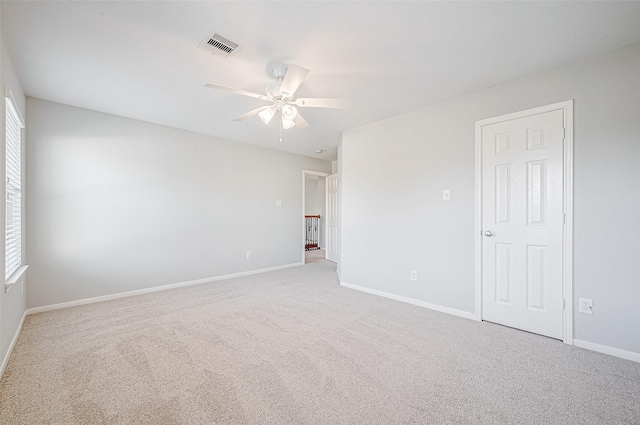 empty room featuring ceiling fan and light carpet