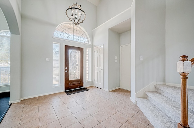 foyer featuring light tile patterned floors, a notable chandelier, and a towering ceiling