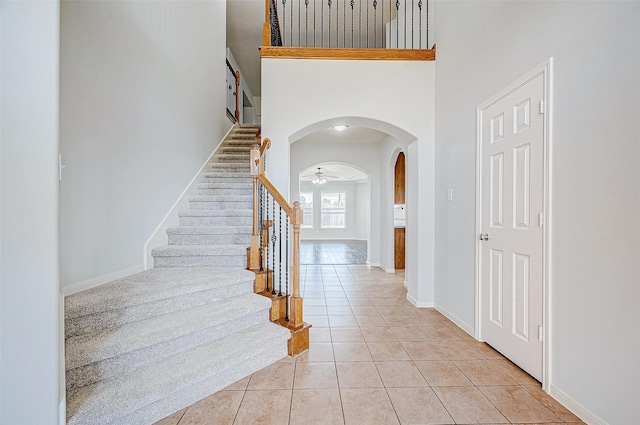 tiled entryway with ceiling fan and a high ceiling