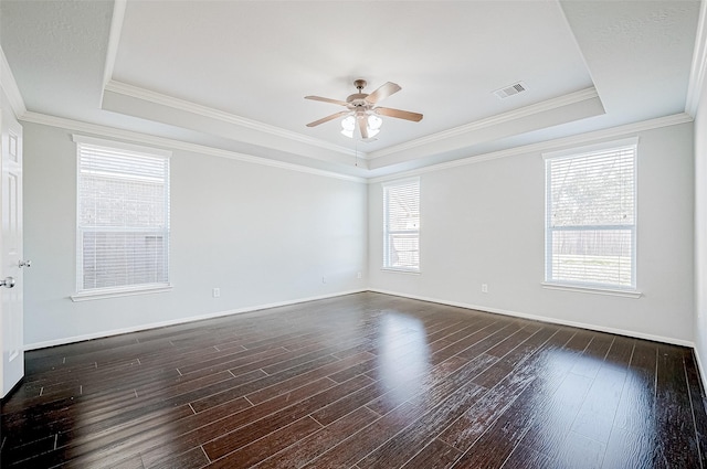 empty room with a raised ceiling, dark wood-type flooring, and a wealth of natural light