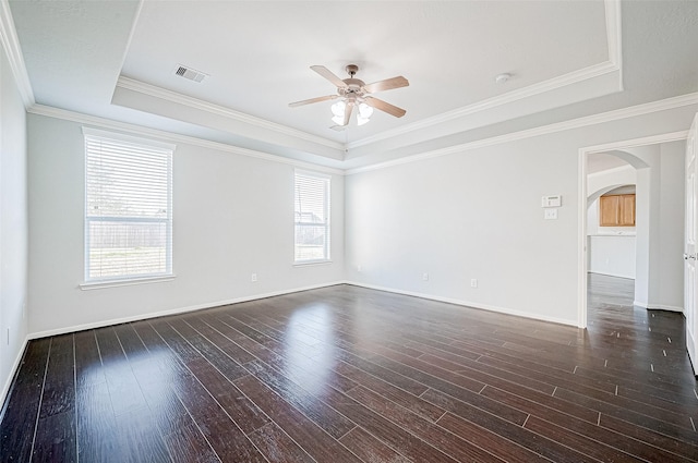 spare room featuring a raised ceiling, crown molding, dark hardwood / wood-style floors, and ceiling fan