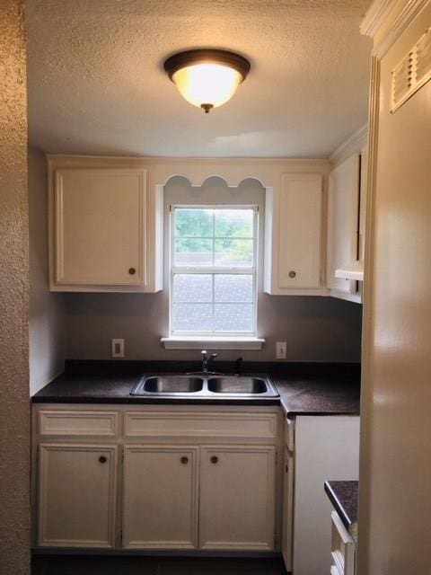 kitchen with white cabinets, stainless steel fridge, a textured ceiling, and sink