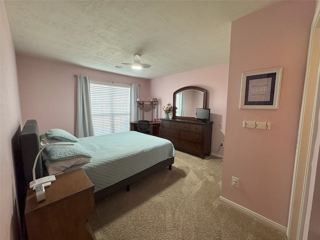 bedroom with ceiling fan, light colored carpet, and a textured ceiling