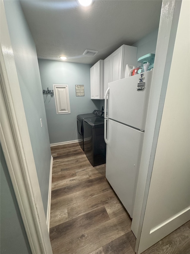 clothes washing area with dark hardwood / wood-style flooring, cabinets, and independent washer and dryer