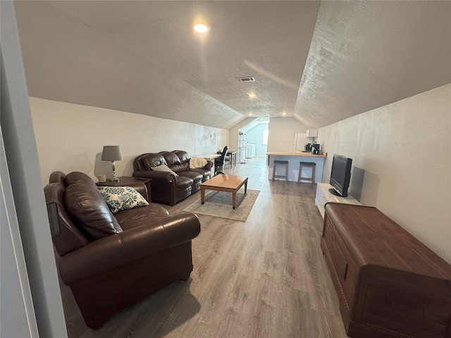 living room with wood-type flooring, a textured ceiling, and vaulted ceiling