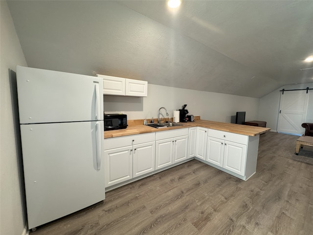 kitchen featuring white refrigerator, white cabinetry, sink, and vaulted ceiling