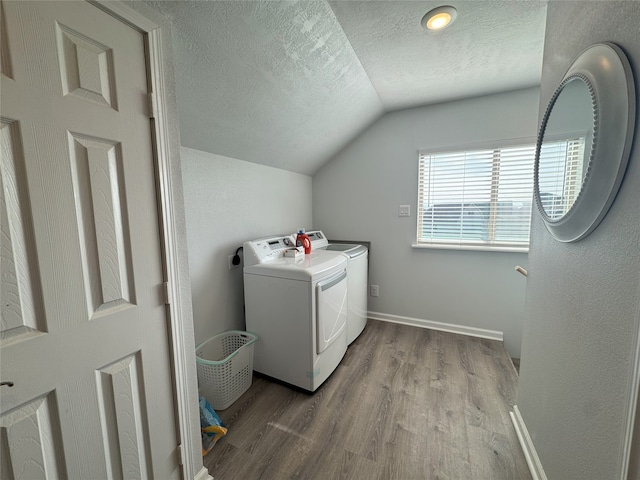 clothes washing area with washer and dryer, a textured ceiling, and light wood-type flooring