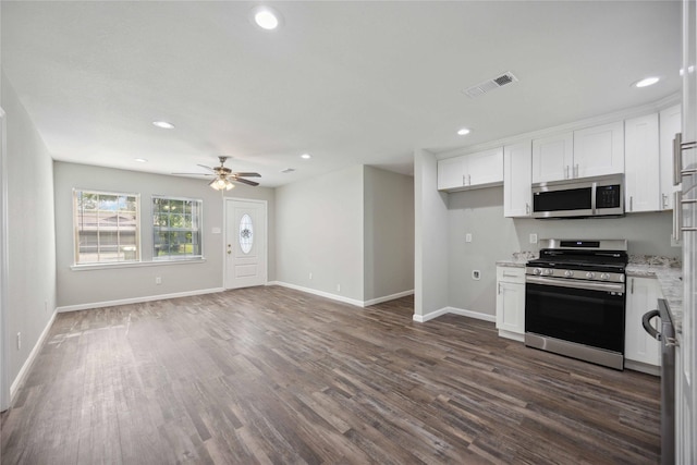 kitchen with dark wood-type flooring, white cabinets, ceiling fan, light stone countertops, and appliances with stainless steel finishes