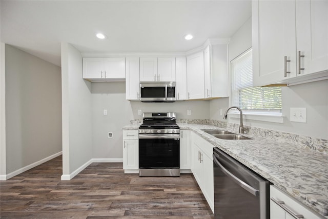 kitchen with light stone countertops, appliances with stainless steel finishes, white cabinetry, and sink