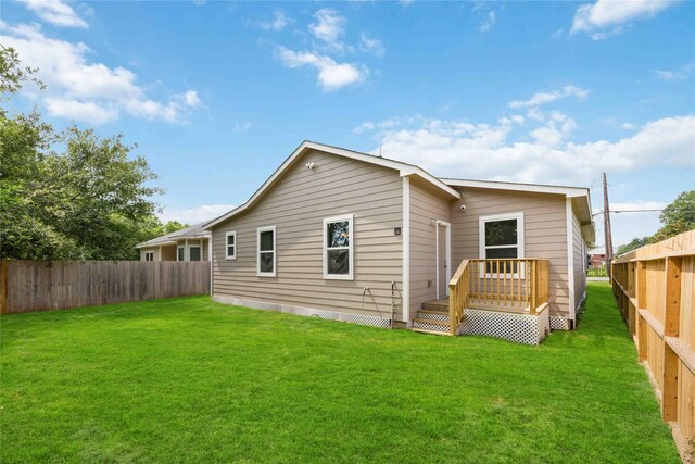 rear view of house featuring a wooden deck and a yard