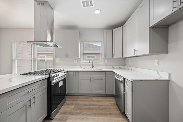 kitchen with gray cabinets, wall chimney exhaust hood, and stainless steel appliances