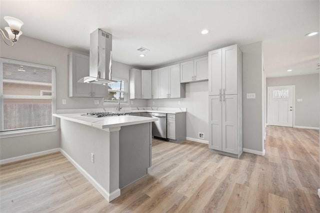 kitchen with island exhaust hood, kitchen peninsula, plenty of natural light, and appliances with stainless steel finishes