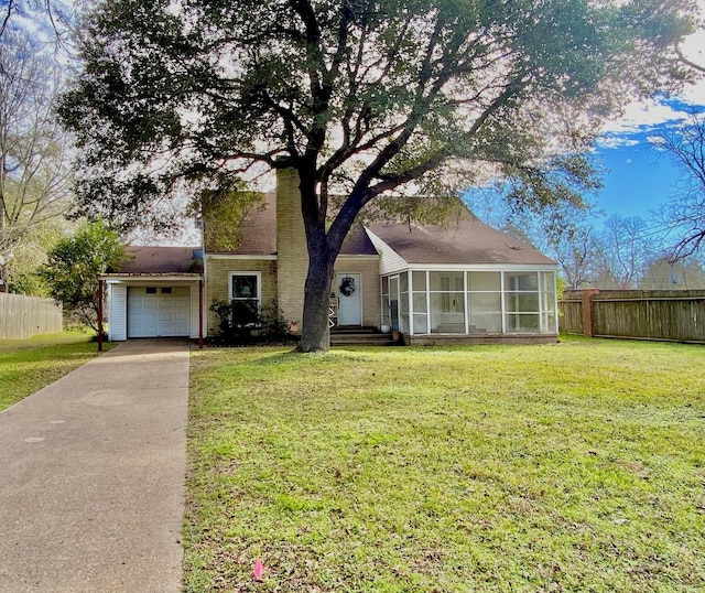 view of front of house featuring a sunroom, a front yard, and a garage