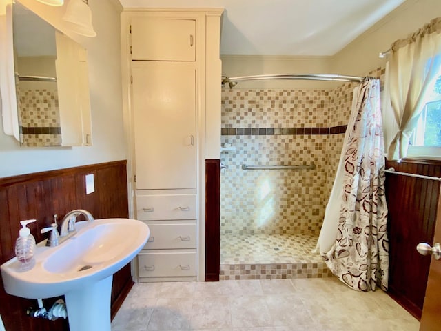 bathroom with curtained shower, wood walls, and sink