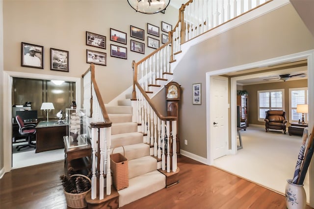 staircase featuring ceiling fan, a towering ceiling, and hardwood / wood-style flooring