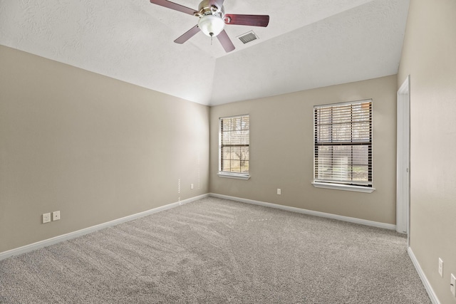 carpeted spare room featuring a wealth of natural light, a textured ceiling, ceiling fan, and lofted ceiling