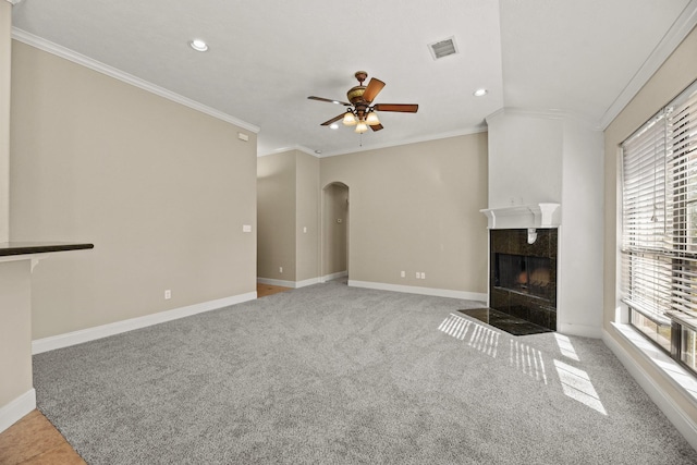 unfurnished living room with crown molding, a high end fireplace, a healthy amount of sunlight, and ceiling fan