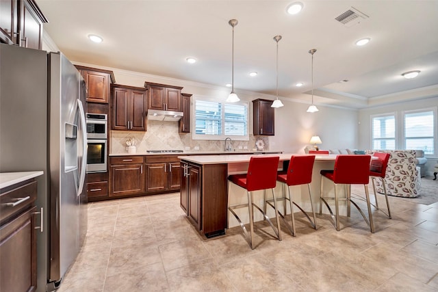 kitchen with dark brown cabinetry, hanging light fixtures, stainless steel appliances, a breakfast bar, and a kitchen island